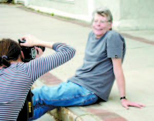 KING AT EASE â€” A photographer takes an upclose shot of author Stephen King, who is sitting on the sidewalk on Main Street in Bridgton. (Geraghty Photos)