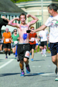 POWERING UP — Flexing while being videotaped running in Bridgton's 4 on the Fourth Road Race was Cullen Bollinger, age 15, of Camp Owatonna in Harrison.