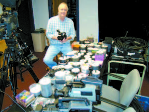 WHY IS THIS MAN SMILING? â€” The $3,500 high-definition video camera held by Lake Region Television Manager John Likshis contains a small card that replaces everything on the table in front of him â€” making DVDs and taped video cameras obsolete. â€œWe may start a museum,â€ he jokes. (Geraghty Photos)