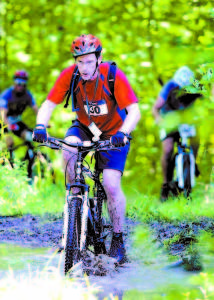 RIGHT THROUGH THE MUD HOLE â€” Mike Adams splashes through mud and water during Saturday's Great Adventure Challenge.