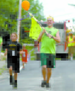 FASTEST SUPER HERO â€” Posting the fastest time at the Super Hero Dash was 9-year-old Mason Stafford. Escorting the winner is race volunteer Murphy McKinley. (Rivet Photos)