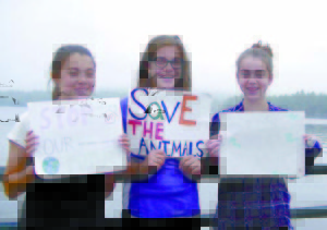 LAKE REGION MIDDLE SCHOOL science students, (left to right) Aisley Sturk, Isabelle Davis-White and Lindsey Keenan, all 14 years old, hold signs on the Naples Causeway. Although the turnout was much smaller than the Peopleâ€™s Climate March in New York City, the students said it was important to educate others about the Greenhouse Effect as well as convincing others to lower their individual carbon footprints. (De Busk Photo)