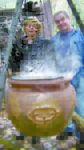 LAURA AND RICK POLAND stand behind a witchesâ€™ cauldron with contents that appear to boil and steam. For the past 17 years, the couple has been changing their yard into an interactive Halloween scene. (De Busk Photo) 