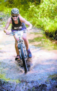 THROUGH A MUD HOLE — Cyclist Candace Sabol of Orono cuts through a mud hole. (Photo by Drew Sanborn)