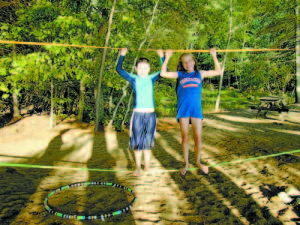 HENRY JOHNSON, 9, of Cape Elizabeth, and his cousin, Julianne Coyne, 12, of South Portland, balance on the Slacker Wave Walker, a mobile tightrope system made from nylon webbing. The cousins were among the visitors who spent a portion of Labor Day at the Sebago Lake State Park day use area. (De Busk Photo)