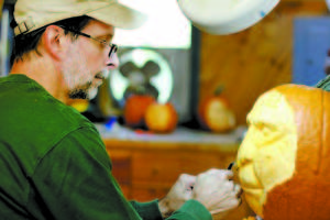 Bill Janelle of West Bridgton carves one of eight faces he will use in a New Hampshire pumpkin-carving contest. (Rivet Photos)