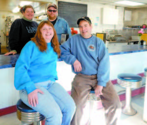 NEW OWNERS BEHIND MELBYâ€™S â€” Wayne and Tracie Hill stand behind the restaurant counter at Melbyâ€™s Market & Eatery, where they will take over ownership Feb. 15 from Paul and Kay Legare, seated.  