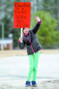 VOTE YES â€” Margo Tremblay waves at passing cars while rallying with other Casco residents on Saturday, April 2 to support the referendum to renovate and re-open Crooked River School. The vote takes place April 12 in all four towns of SAD 61.