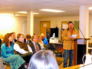 BATTLE LINES â€” Robert Tyszka, at podium, testified Tuesday before the Bridgton Planning Board in opposition to placement of a bulk propane storage facility at the end of Raspberry Lane, where he and 11 other families live. Seated from left are three persons representing Stone Road Energy, LLC, formerly Bridgton Bottled Gas: Jodi Ameden, a Vermont-based energy consultant; Josh Sandahl, Stone Roadâ€™s Director of Finance; and Stone Road attorney Christian Chandler. Rita Tyszka is seated behind them. (Geraghty Photo) 