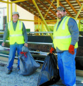 A HELPFUL HAND â€” Employees Richard Welch and Joe Vaughn toss household trash into the bin on a Wednesday in June. The Brownfield Transfer Station received the Most Improved Transfer Site Award from the Maine Resource Recovery Station recently. (De Busk Photo)  
